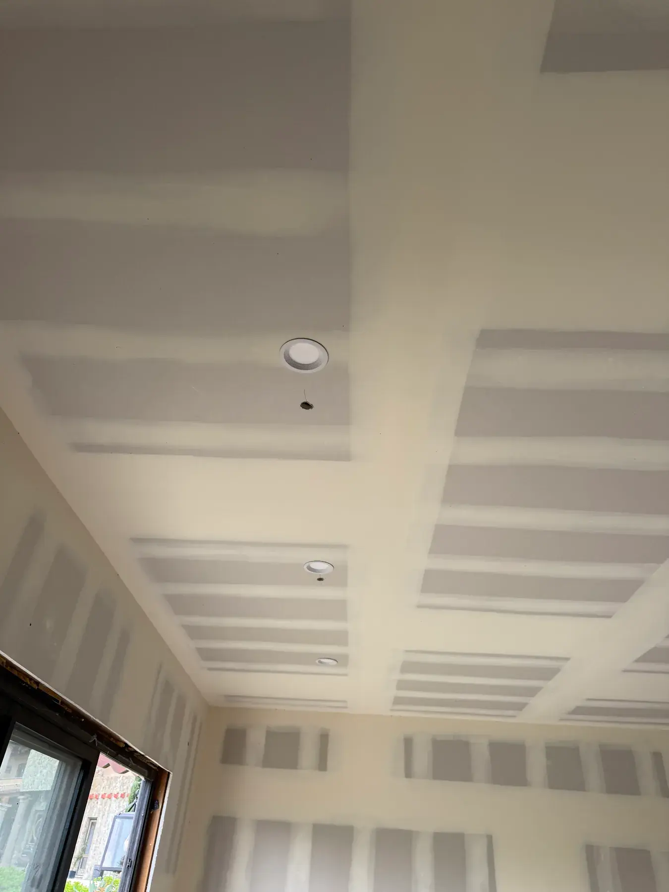 Coffered ceiling with taped and mudded drywall seams and recessed can lights installed