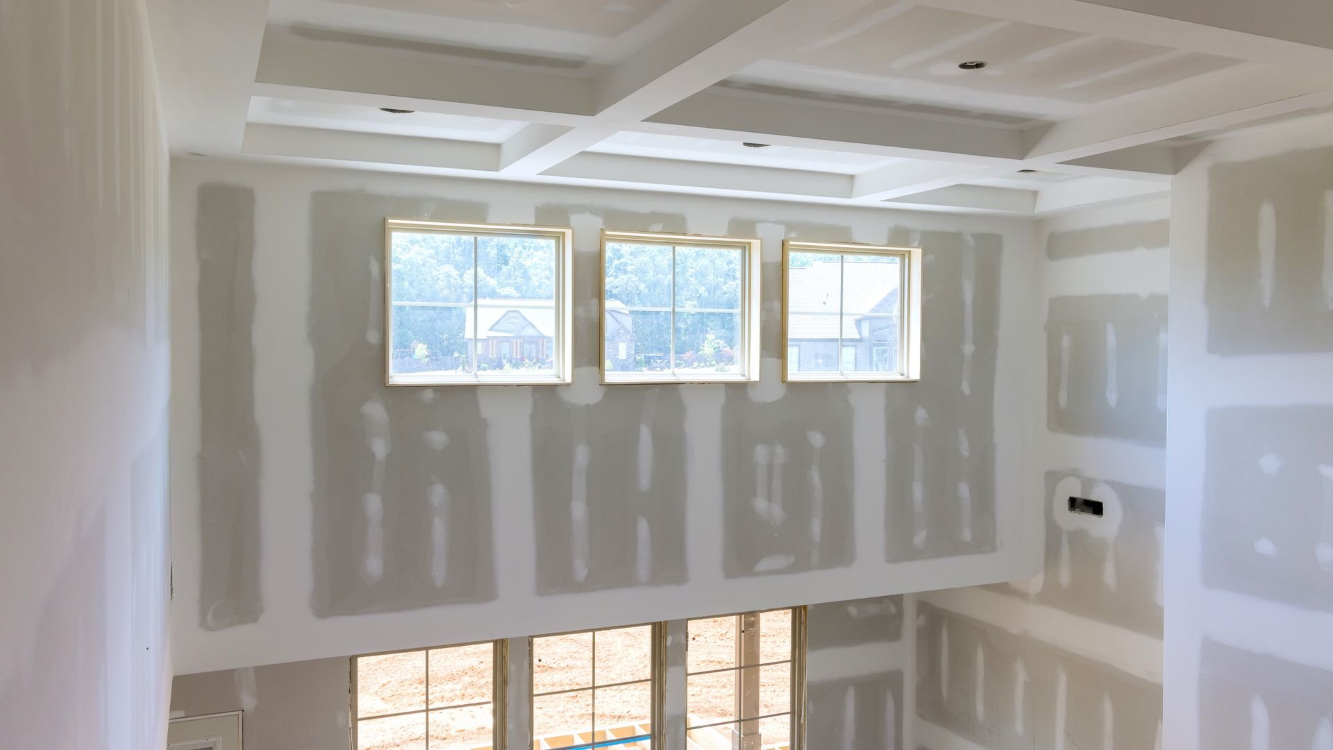 Unfinished room with three windows and coffered ceiling during construction