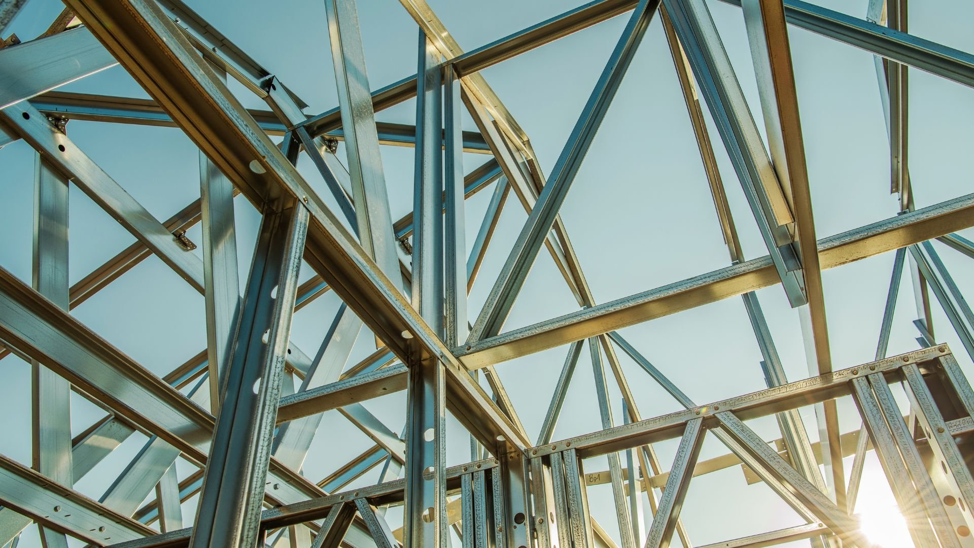 Steel construction beams intersecting against a blue sky background