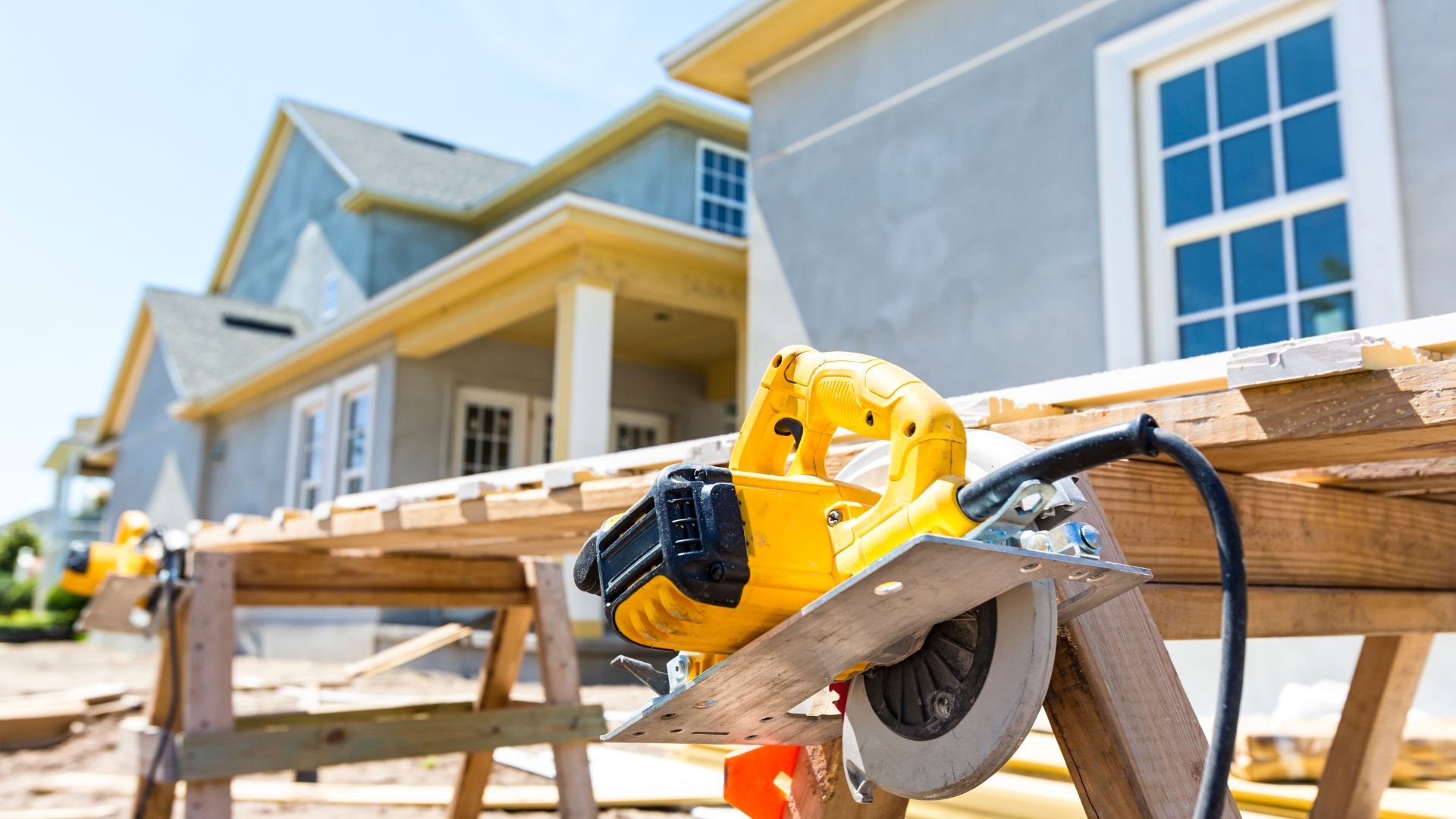 Yellow circular saw on wooden planks during house construction