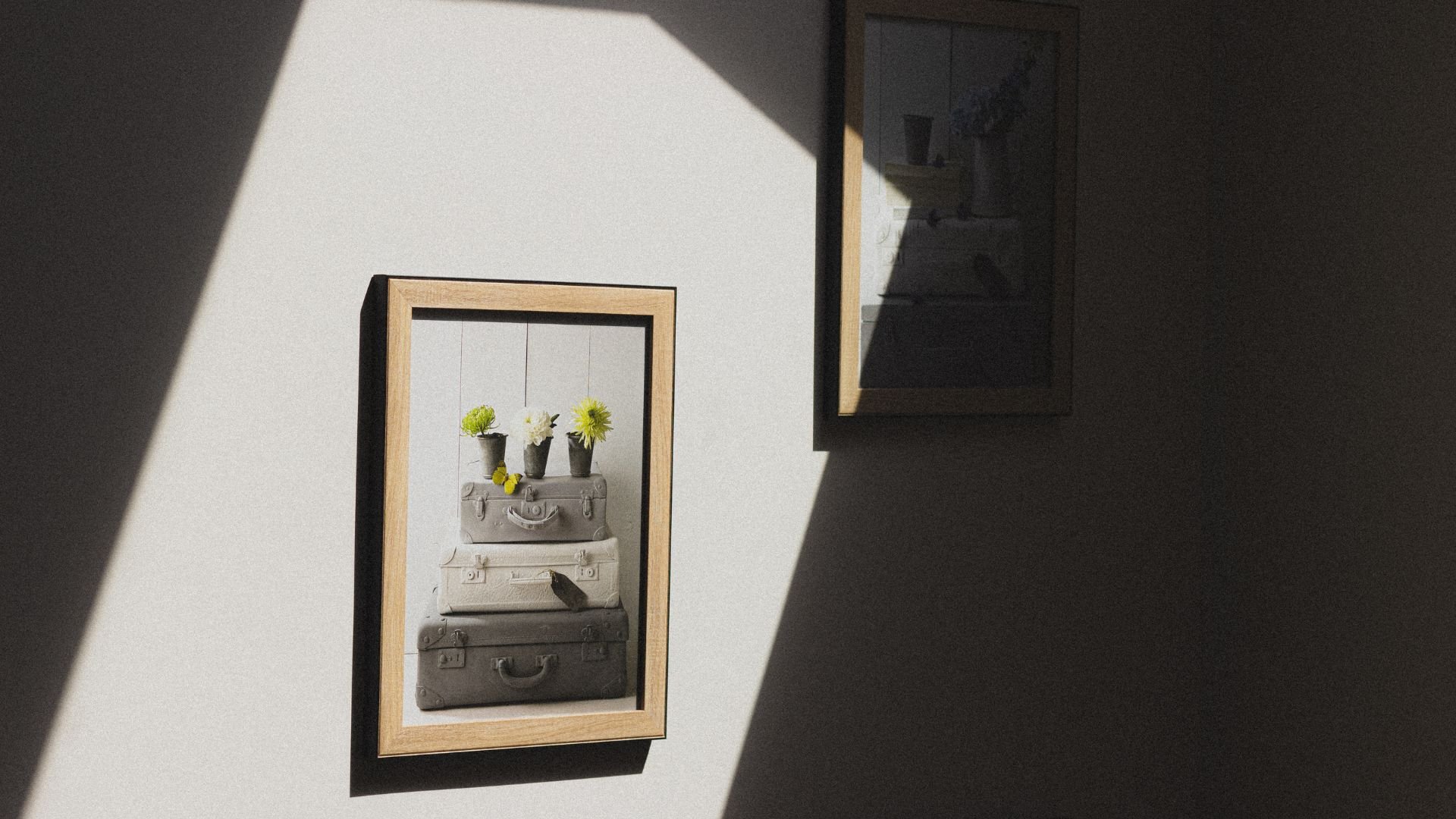 Framed artwork of vintage suitcases with yellow flowers in monochrome